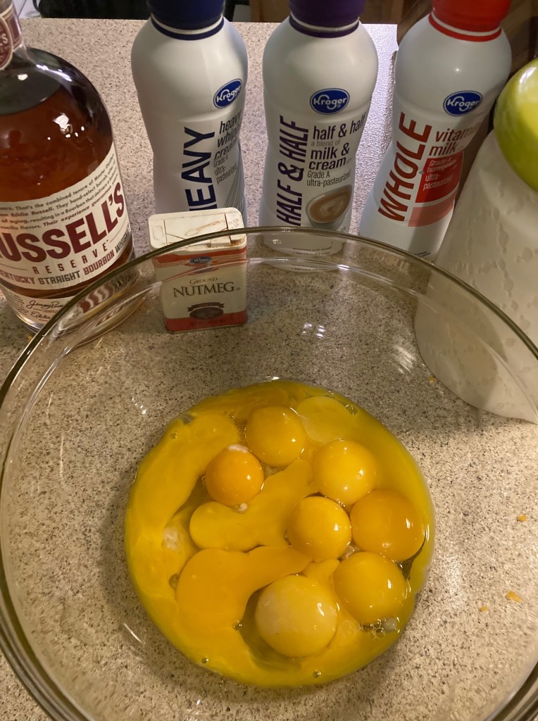 Gathered ingredients for aged eggnog with egg yolks separated from egg whites. 
